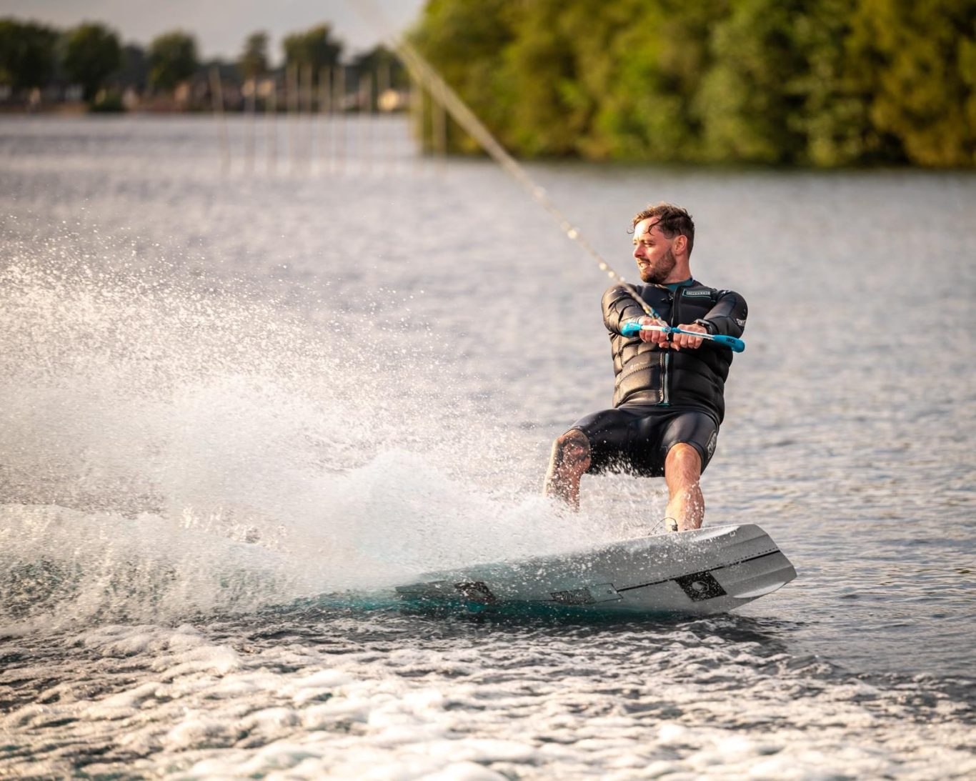 A person wakeboarding on a lake against a backdrop of greenery.