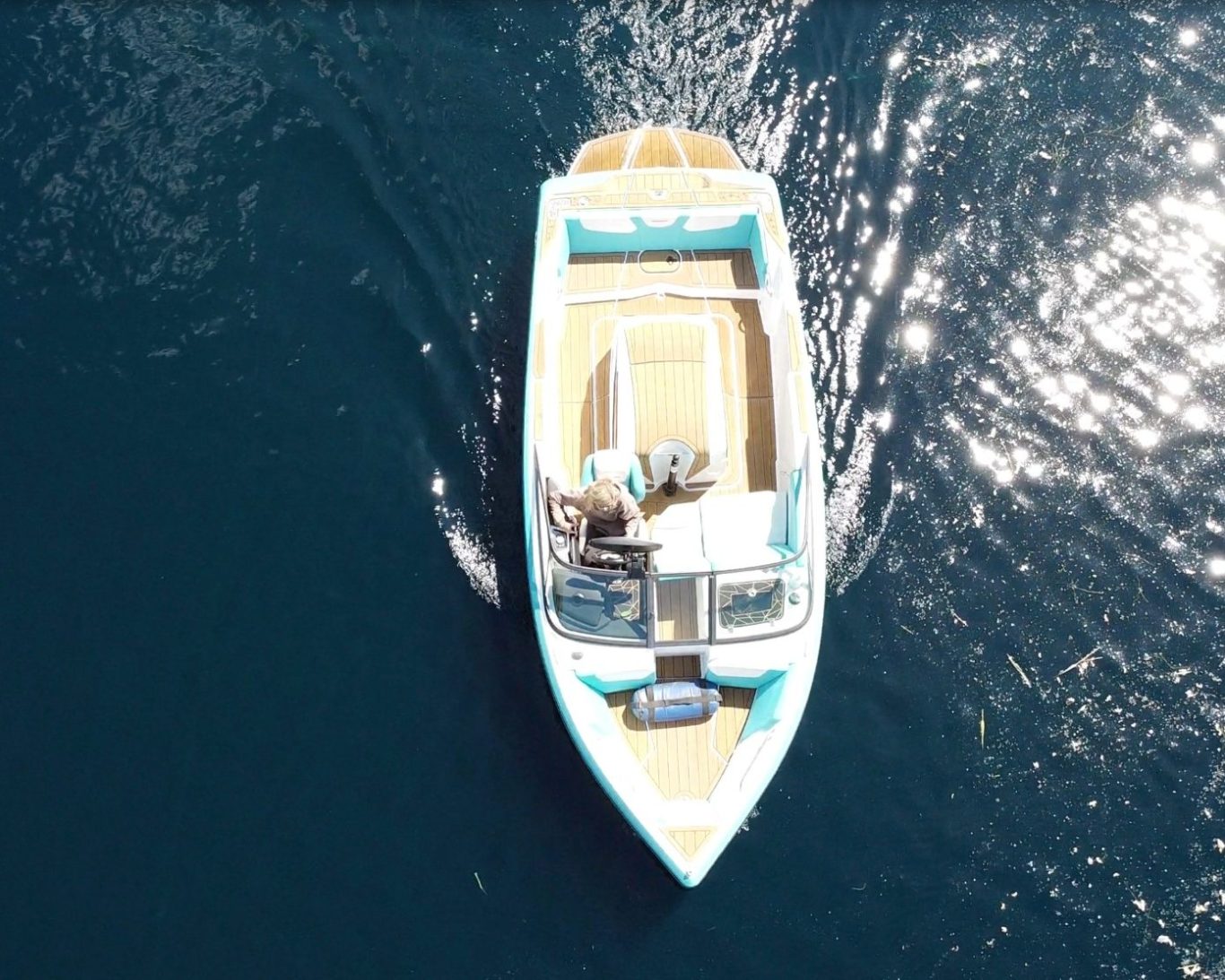 Aerial view of a water ski boat on calm blue water.