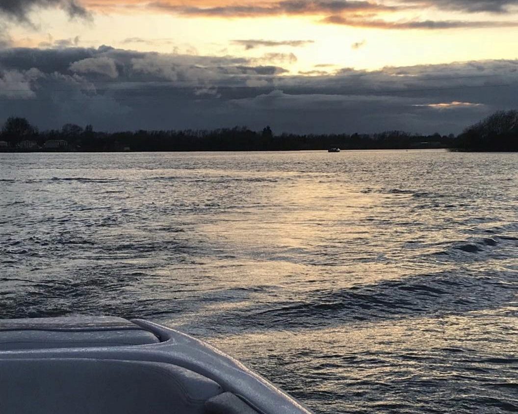 Sunset over a body of water with rippling waves and a cloudy sky in the background.